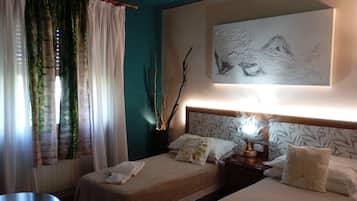 Una camera d'albergo con due letti, un comodino con una lampada, un quadro appeso al muro e una finestra con tende.