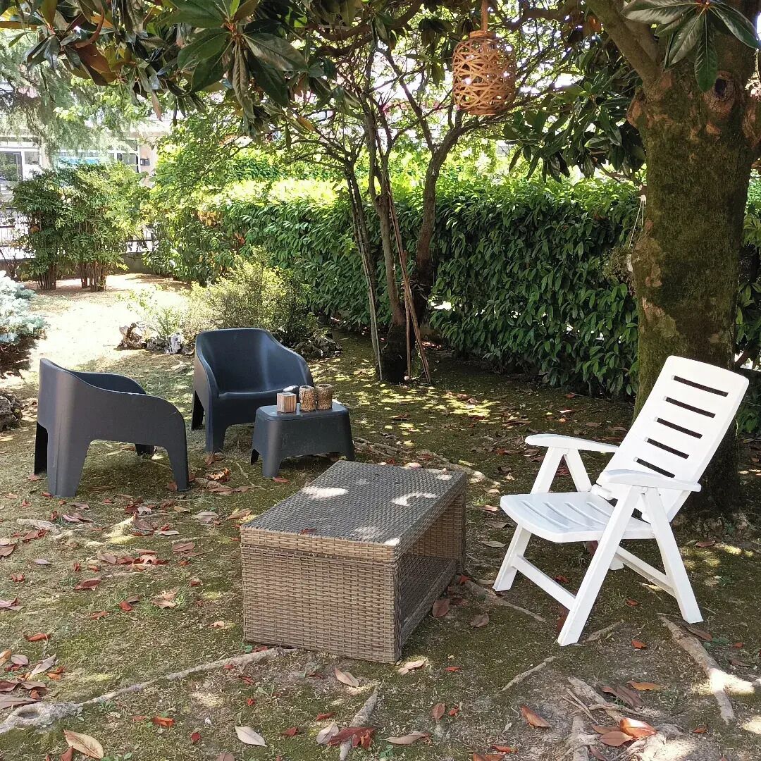 Un espacio de estar al aire libre con mobiliario de mimbre y una silla blanca.