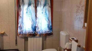 Une salle de bain comprenant des toilettes, un bidet et un espace douche.