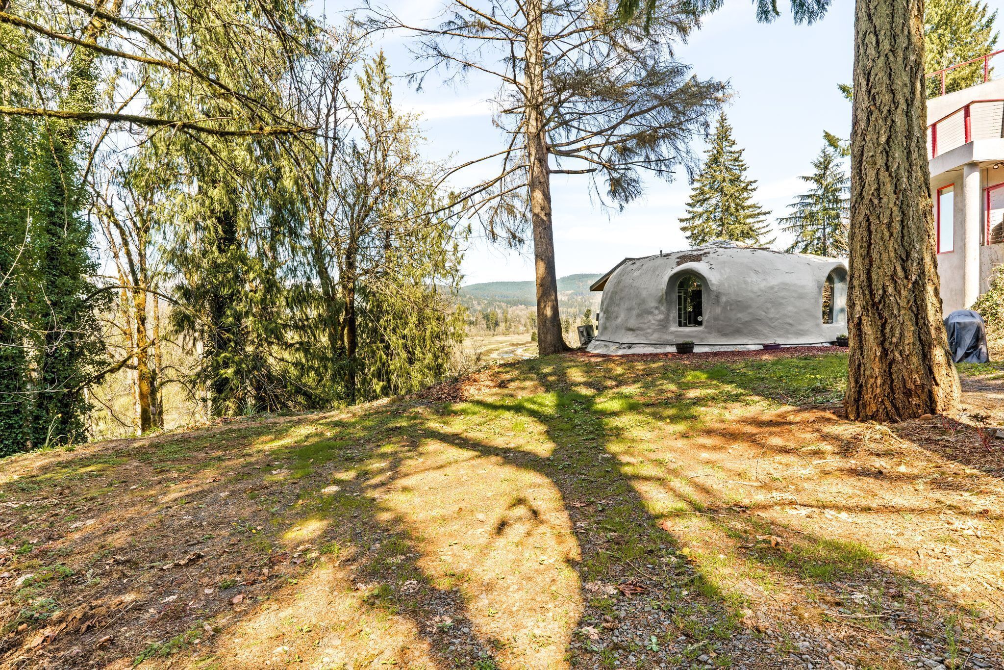 Une cabane rustique située dans une zone boisée, accessible par un sentier de terre.