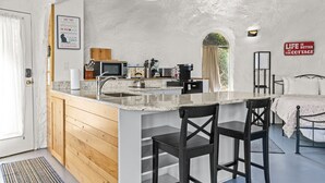 Una cocina compacta con una isla central, armarios de madera, un microondas y una cafetera.