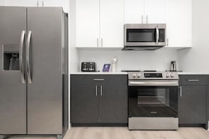A modern kitchen with a stainless steel refrigerator, a microwave, a toaster, and an oven.