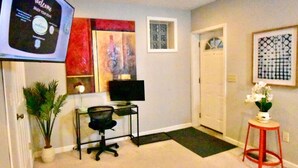 Un espacio de trabajo en casa con escritorio, silla, ordenador y televisor mostrando una pantalla de bienvenida.
