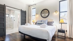 Een slaapkamer met een groot bed, een schuifdeur, een wandlamp en uitzicht op de omgeving.