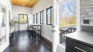 Een moderne keuken met donker houten vloeren, een houten plafond en grote ramen met uitzicht op de omgeving.