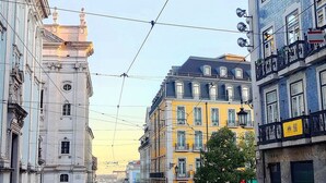 A street with tram tracks, buildings with balconies, and pedestrians. - Cozy Suite in Bairro Alto Shared House (Lisboa)