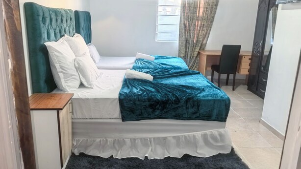 A bedroom with a bed, a desk, and a chair. - Affordable Guest House in Goodwood (Cape Town)