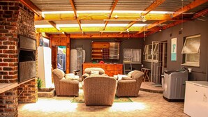 A cozy living room with a fireplace, comfortable seating, and a kitchen area. - Affordable Guest House in Goodwood (Cape Town)