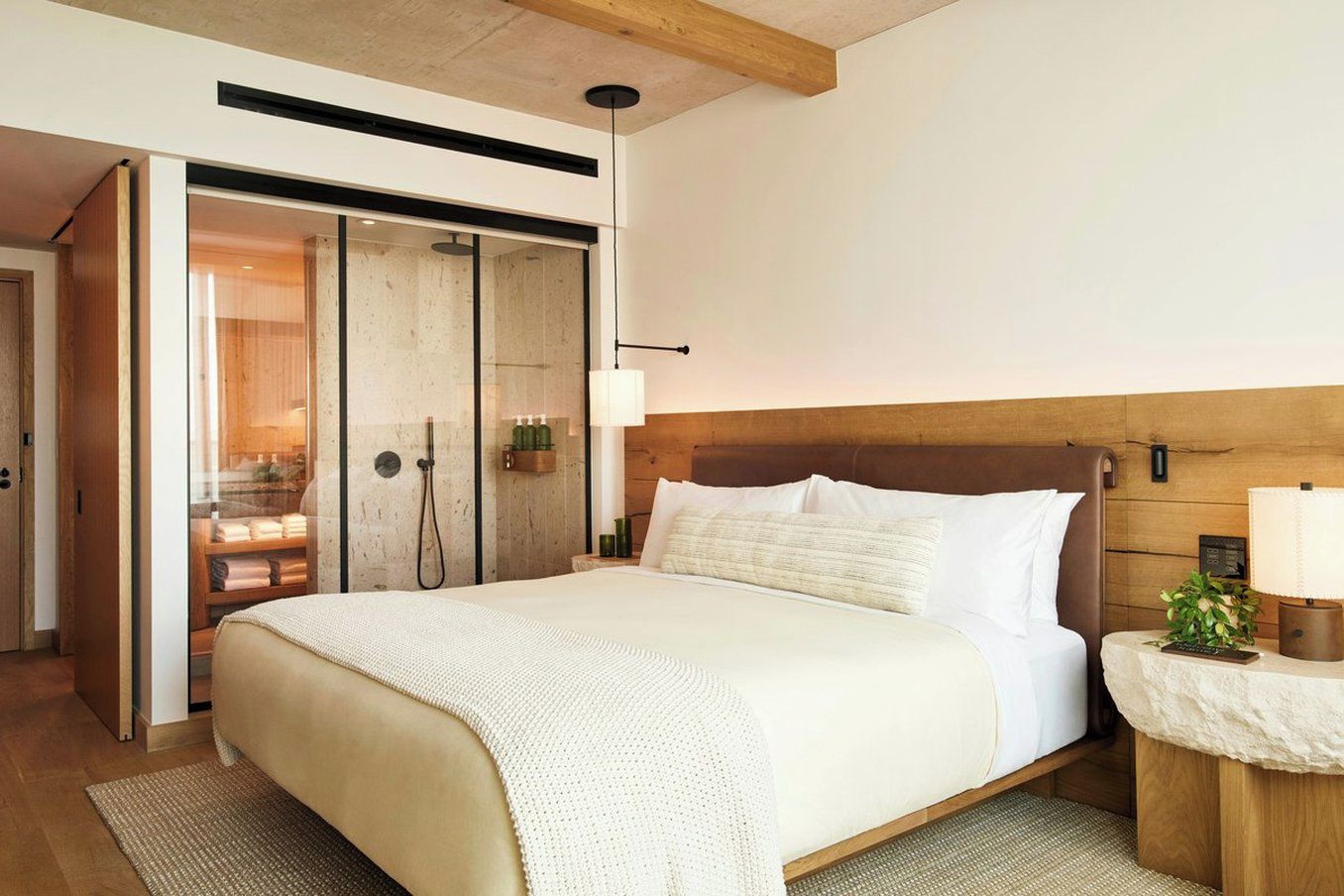 Un dormitorio moderno con una cama grande, cabecera de madera y una mesita de noche con lámpara.