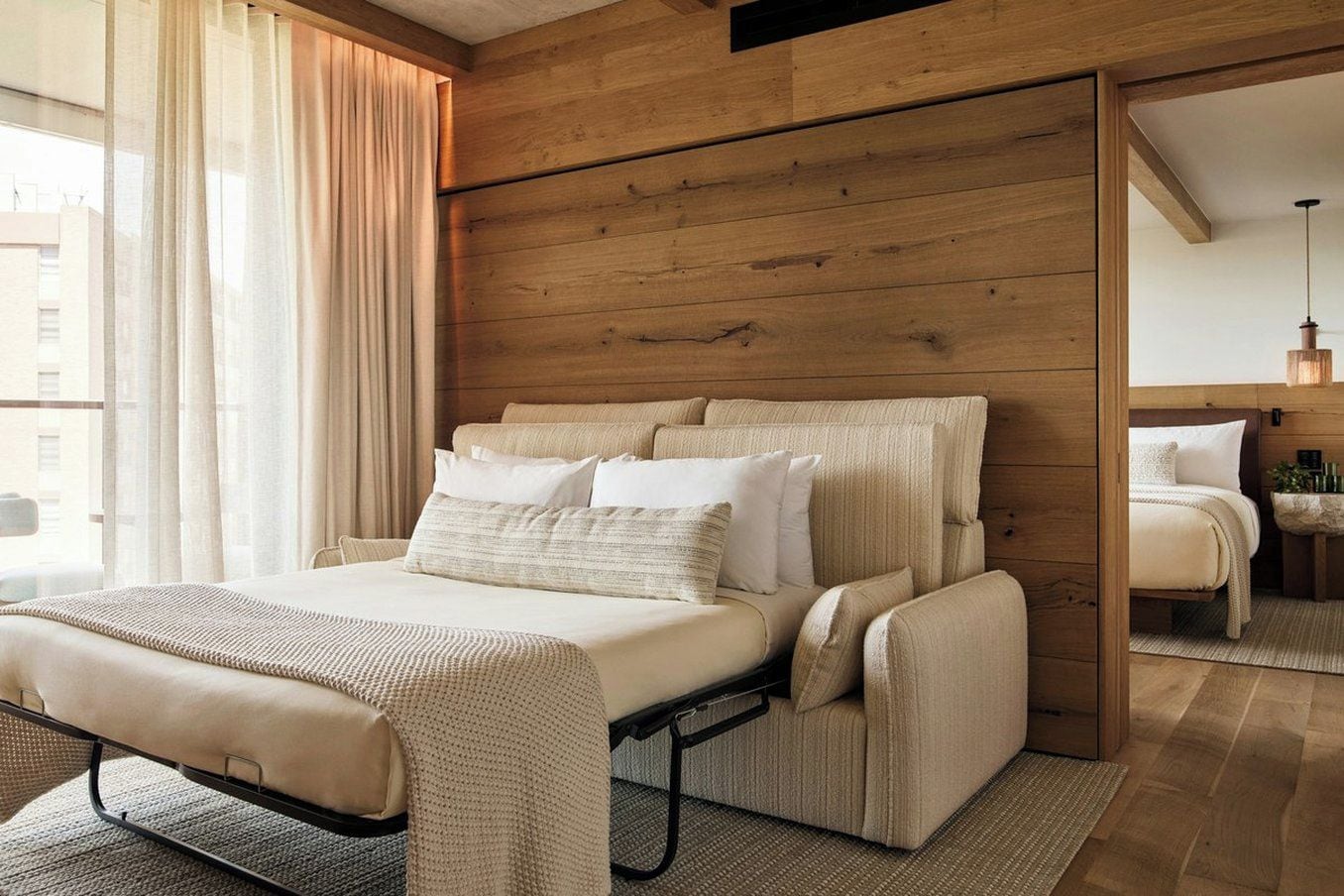 A modern bedroom with a bed, bedside tables, and a mirror.