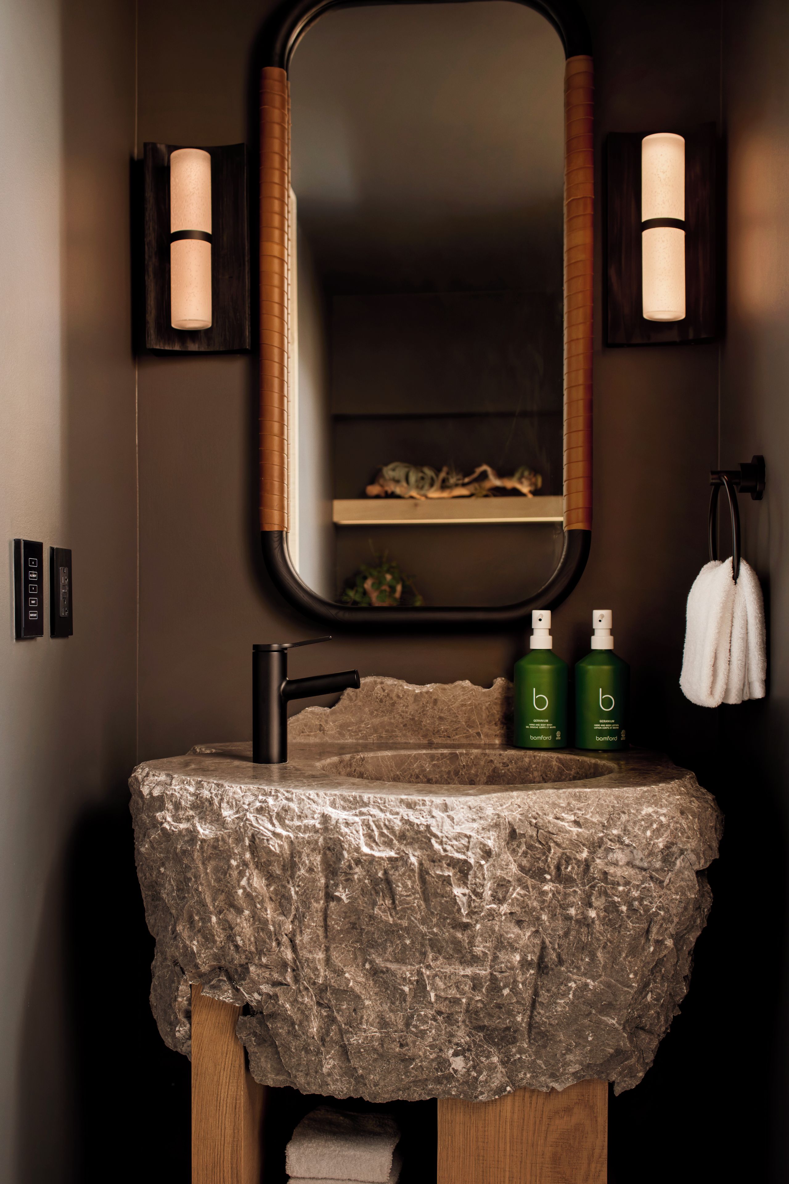 A bathroom with a stone sink, a mirror, and two wall-mounted lights.