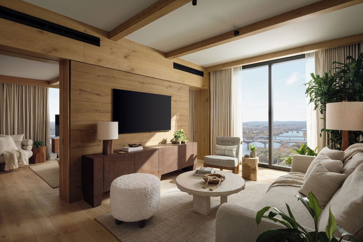 A modern living room with a large TV, wooden beams, a sofa, a coffee table, and a view of a cityscape.