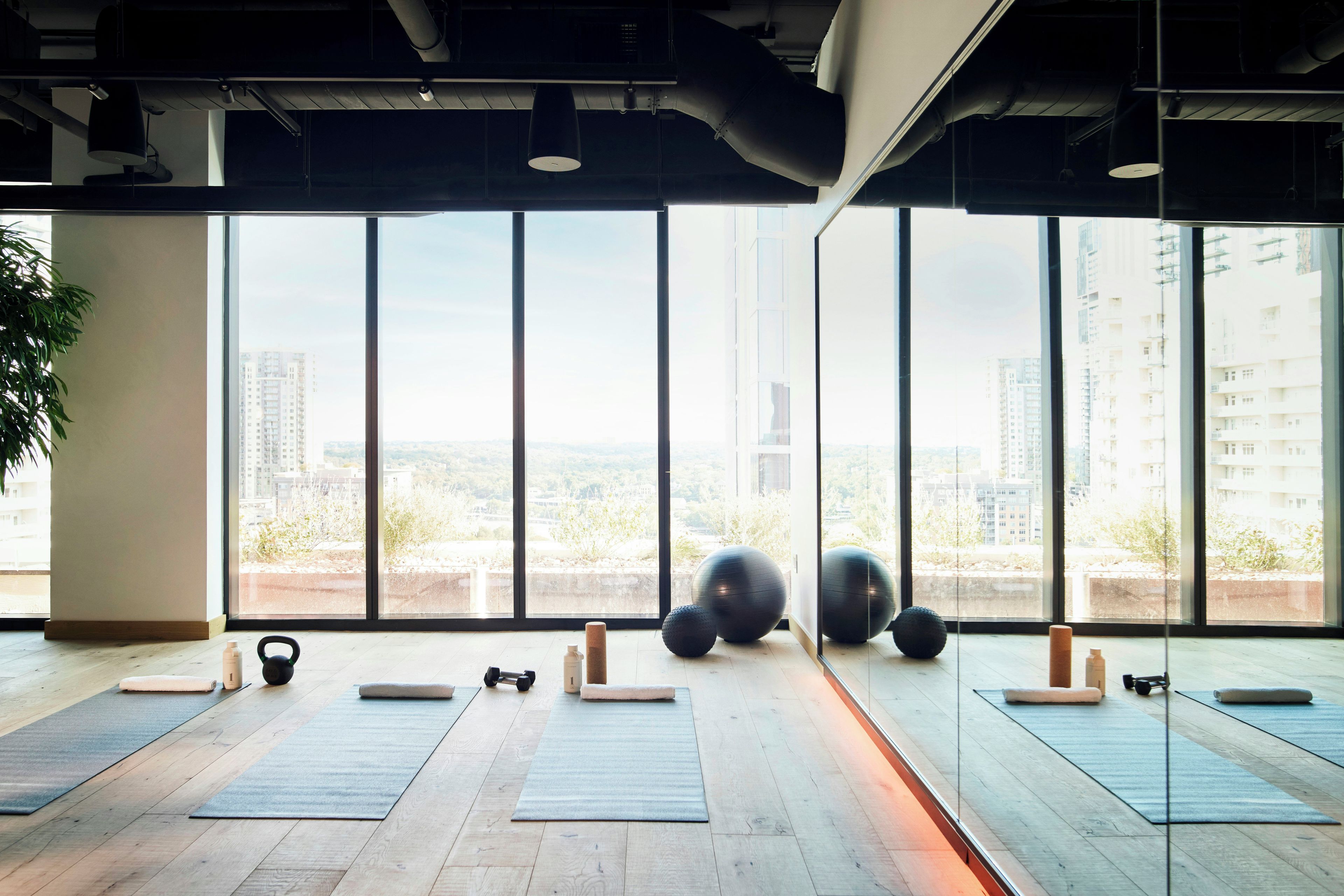 A spacious room with large windows, exercise equipment, and a view of a cityscape.