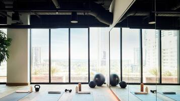 A spacious room with large windows, exercise equipment, and a view of a cityscape.