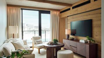 A modern living room with a sofa, armchairs, a coffee table, and a TV mounted on a wooden wall.