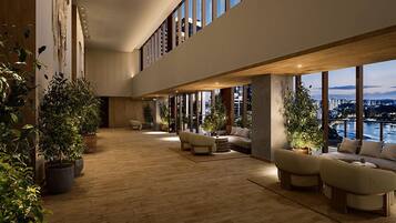 A spacious indoor area with large windows, multiple seating arrangements, and potted plants.