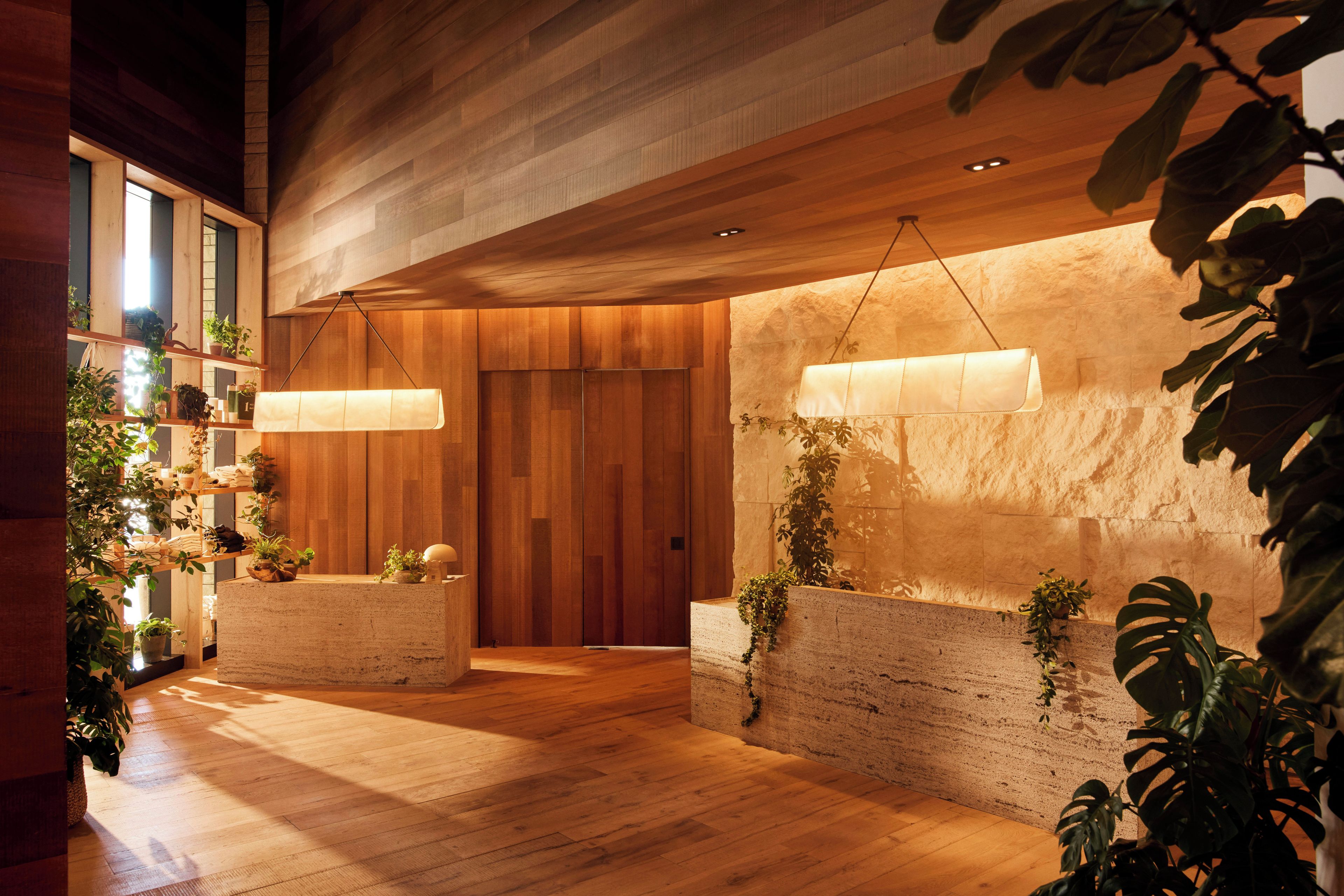 A modern interior with wooden flooring, a reception desk, and hanging pendant lights.