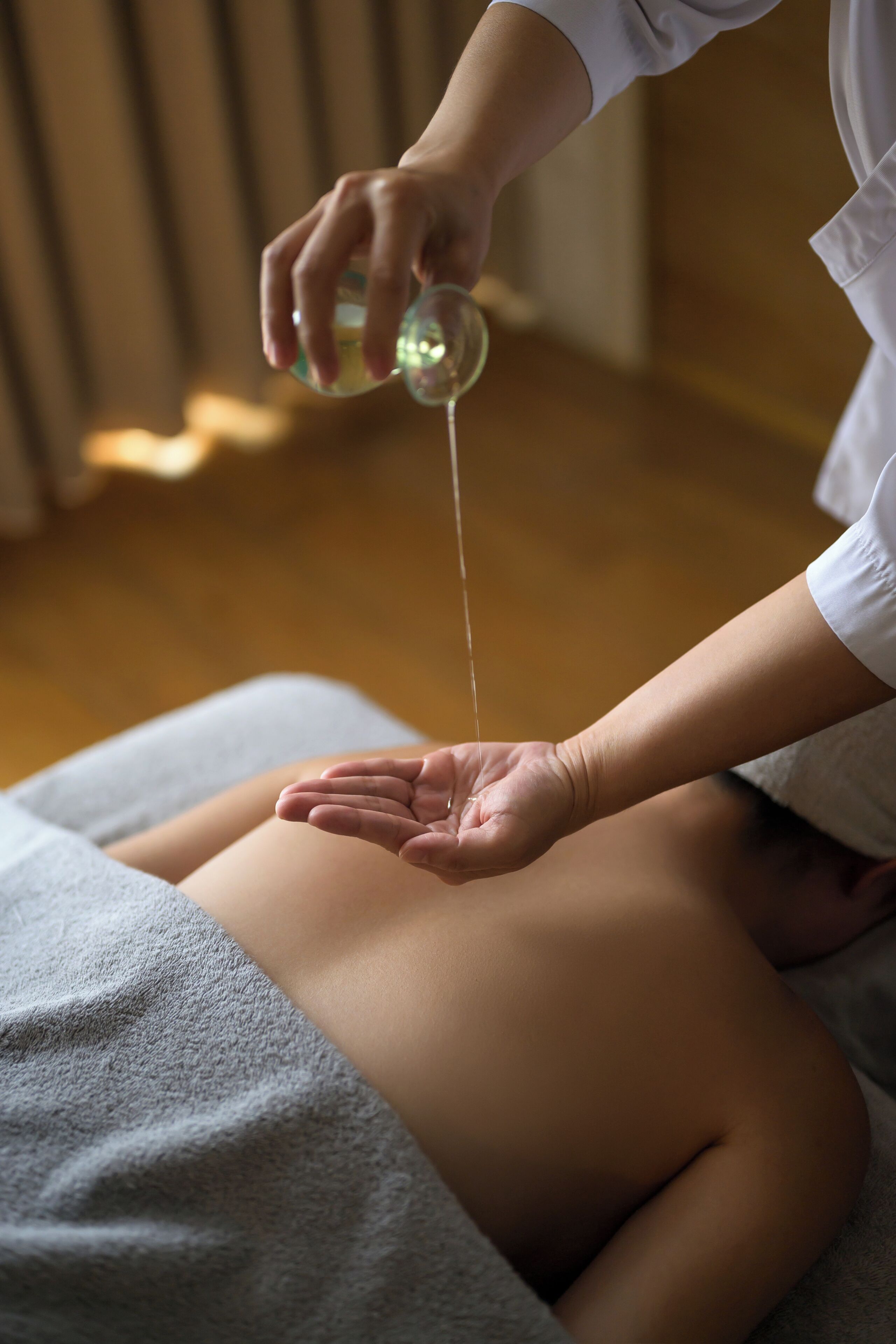 Eine Person erhält eine Rückenmassage, während Öl auf den Rücken gegossen wird.