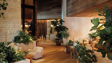 A spacious lobby with a high ceiling, wooden flooring, and a variety of seating arrangements.
