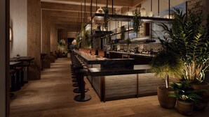 A modern bar area with a long counter, stools, and potted plants.