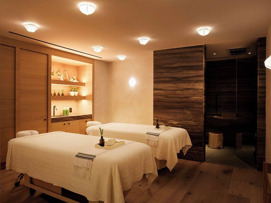 Ein Spa-Raum mit zwei Behandlungsbetten, Holzschränken und einem Spiegel.