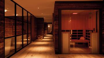 A hallway with wooden walls and a glass partition, leading to a room with a wooden bench and a small table.