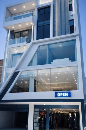 A multi-story building with a glass facade, an open entrance, and a sign indicating it's open. - Charming 3-bedroom apartment . Luxury Penthouse  Stunning Himalayan Views (Kathmandu)