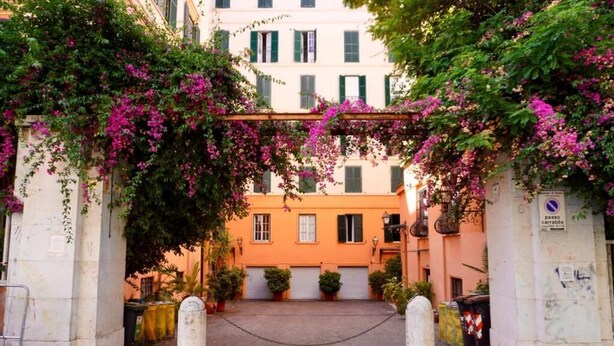 Ein Innenhof mit Tor, Blumentöpfen und einem Gebäude mit Balkon.