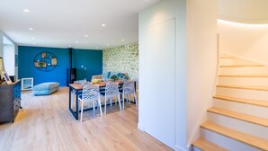 Ein modernes Wohnzimmer mit Essbereich, einer Treppe und einer Steinwand.