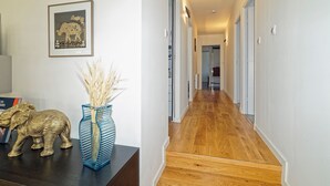 Un pasillo con piso de madera, un cuadro en la pared y una figurita decorativa de elefante sobre una mesa.
