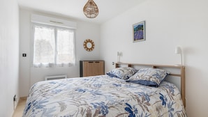 A bedroom with a bed, a window, a wall decoration, and a hanging light fixture. - La Brise d'Agde - 3km de la Plage (Agde)