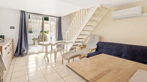 A modern living room with a wooden table, a sofa, and a staircase. - La Pause Valrassienne - 1km de la Plage (Valras-Plage)