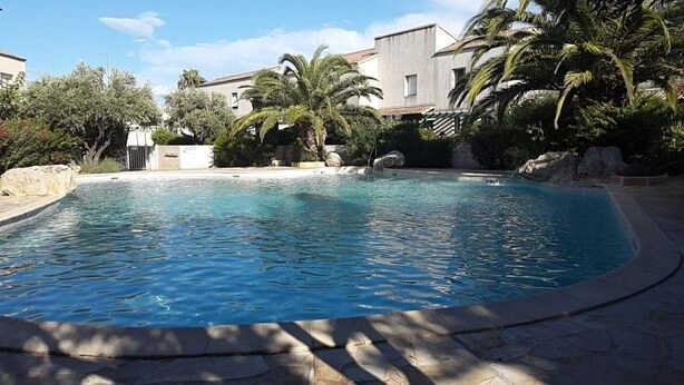 A swimming pool surrounded by palm trees and a building. - La Pause Valrassienne - 1km de la Plage (Valras-Plage)