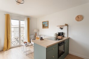 Eine kompakte Küche mit Einbauherd, einer kleinen Kochinsel und Blick auf den Balkon.