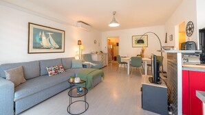 Ett modernt vardagsrum med en soffa, ett soffbord och en matplats med stolar och ett bord.