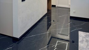 Ein moderner Flur mit glänzendem schwarzen Boden, weißen Wänden und eingelassener Beleuchtung.