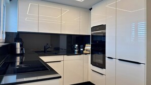 Eine moderne Küche mit weißen Schränken, schwarzen Arbeitsplatten und eingebauten Geräten.