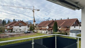 Ein Wohngebiet mit Häusern, einem Baukran und Bergen im Hintergrund.