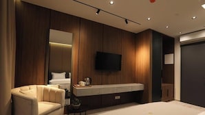 A modern bedroom with a large bed, a sofa, a TV, and a wooden panel wall. - Resort Anës Drinit  (Radac)