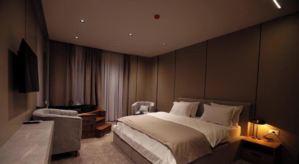 Un dormitorio moderno con una cama grande, mesitas de noche, un escritorio y una silla.