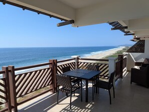 A balcony with a view of the ocean, a table, and chairs. - 1373  Ocean Front 2 bedroom (Bajos de Chila)