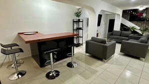 Un salon moderne avec un coin bar, des canapés gris et un escalier.
