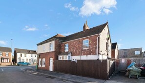 A two-story brick building with a white front door, a small porch, and a wooden fence. - 234 Birstol Rd Apt, Gloucester (Gloucestershire)