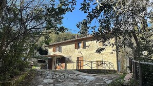 A stone building with a wooden door and windows, surrounded by trees and a stone pathway. - La Funambola B&B (Figline e Incisa Valdarno)