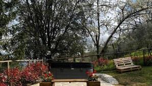A hot tub in a garden with a wooden deck, surrounded by trees and red foliage. - La Funambola B&B (Figline e Incisa Valdarno)
