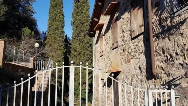 A stone building with a metal gate, tall trees, and a clear sky. - La Funambola B&B (Figline e Incisa Valdarno)