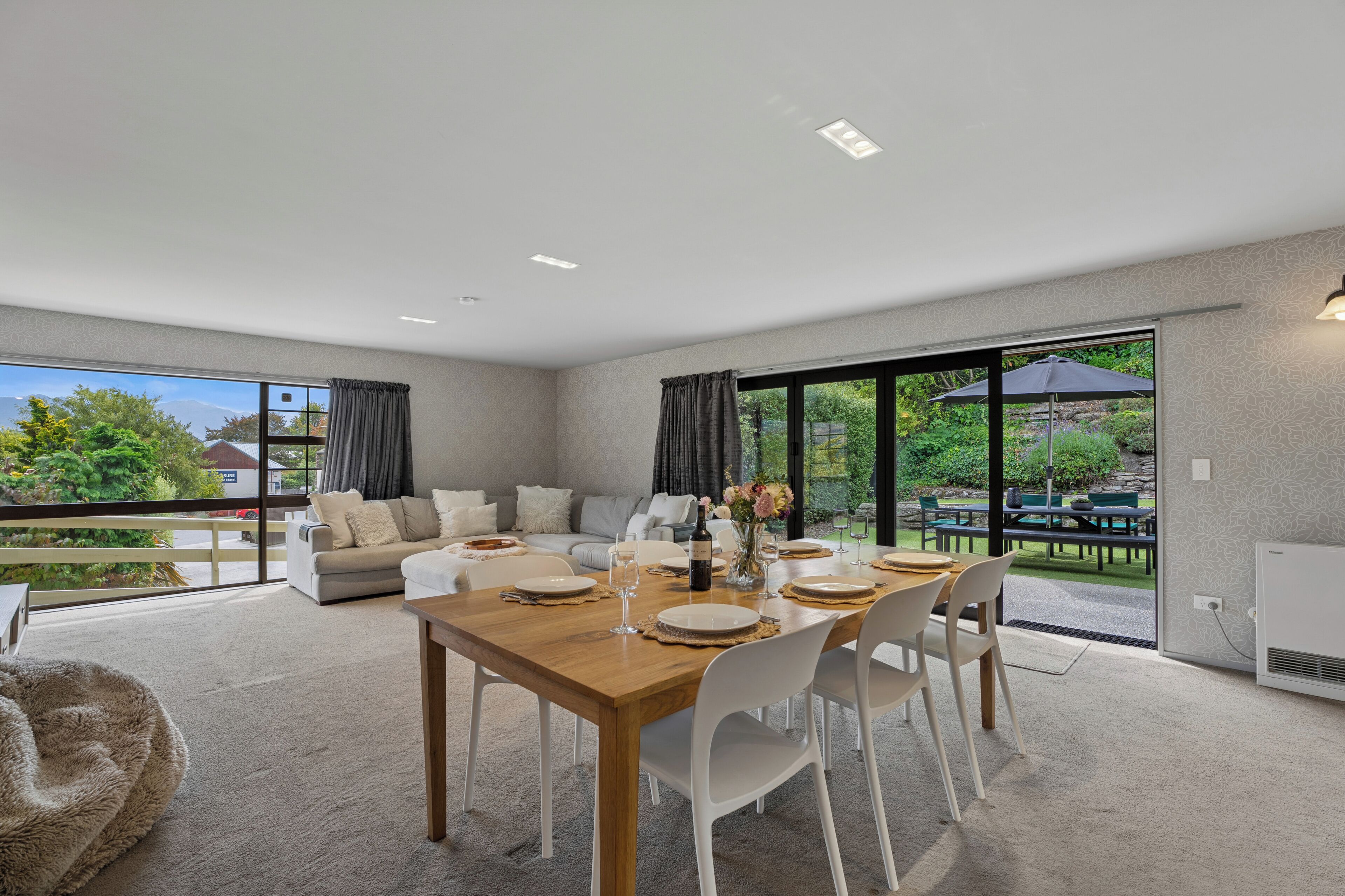 A modern living room with a dining area, large windows, and a view of the outdoors.