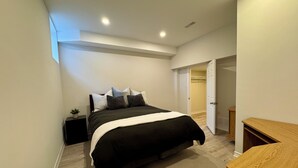 A bedroom with a bed, bedside tables, a nightstand, a wooden dresser, and a closet. - Newly constructed apartment located near Canada’s Wonderland, Vaughan Mills Mall (Vaughan)