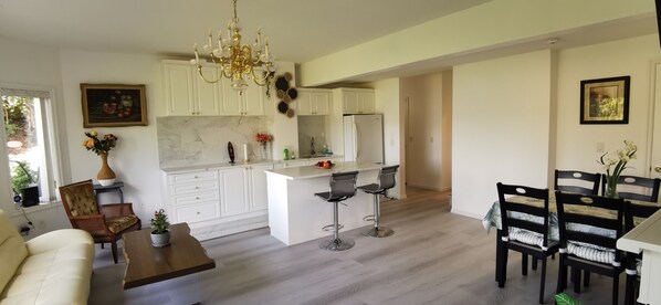 Een moderne keuken met witte kasten, een centraal eiland en barstoelen.