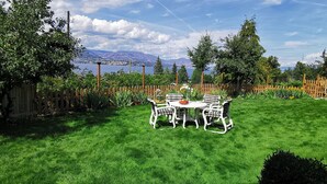 A well-maintained backyard with a dining table and chairs, surrounded by a wooden fence and lush greenery. - New 3BR Guest Suite |  Lakeview,  Private Entry (Kelowna)